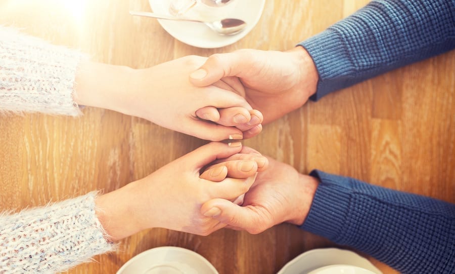 Man and woman holding hands over coffee table